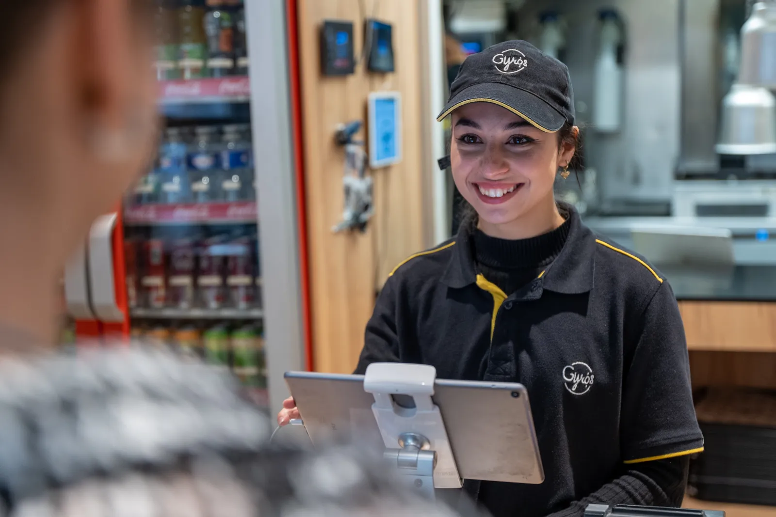 Employée en salle prenant une commande sur tablette, derrière son comptoir