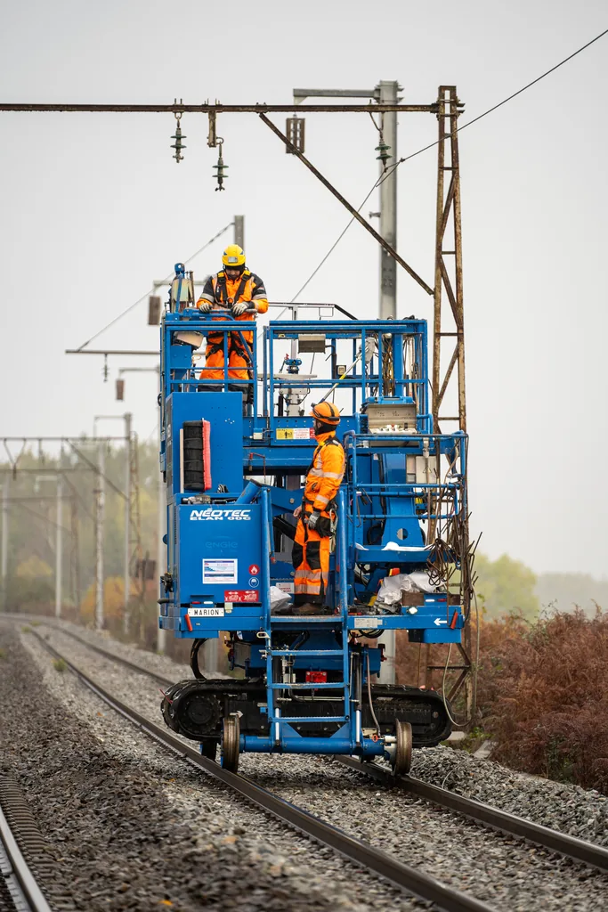 Deux techniciens sur une nacelle, en intervention sur une caténaire ferroviaire