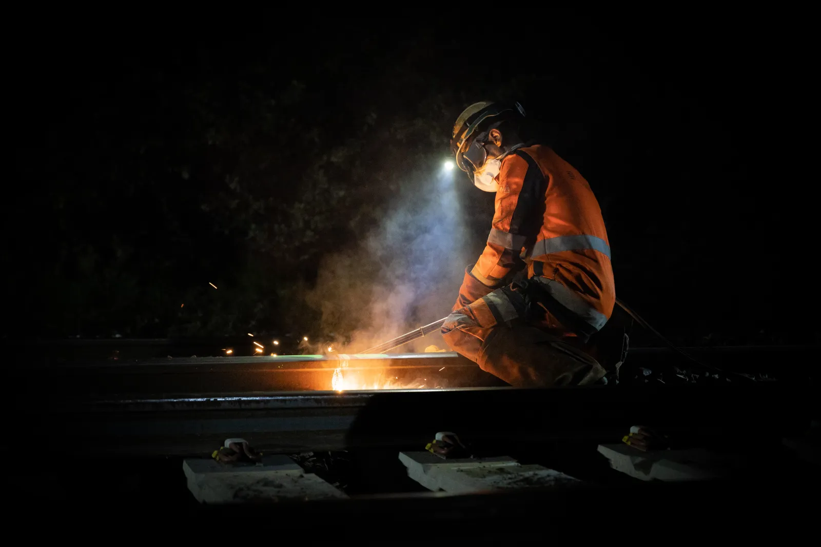 Intervention sur un rail en pleine nuit, dans une gerbe d'étincelles